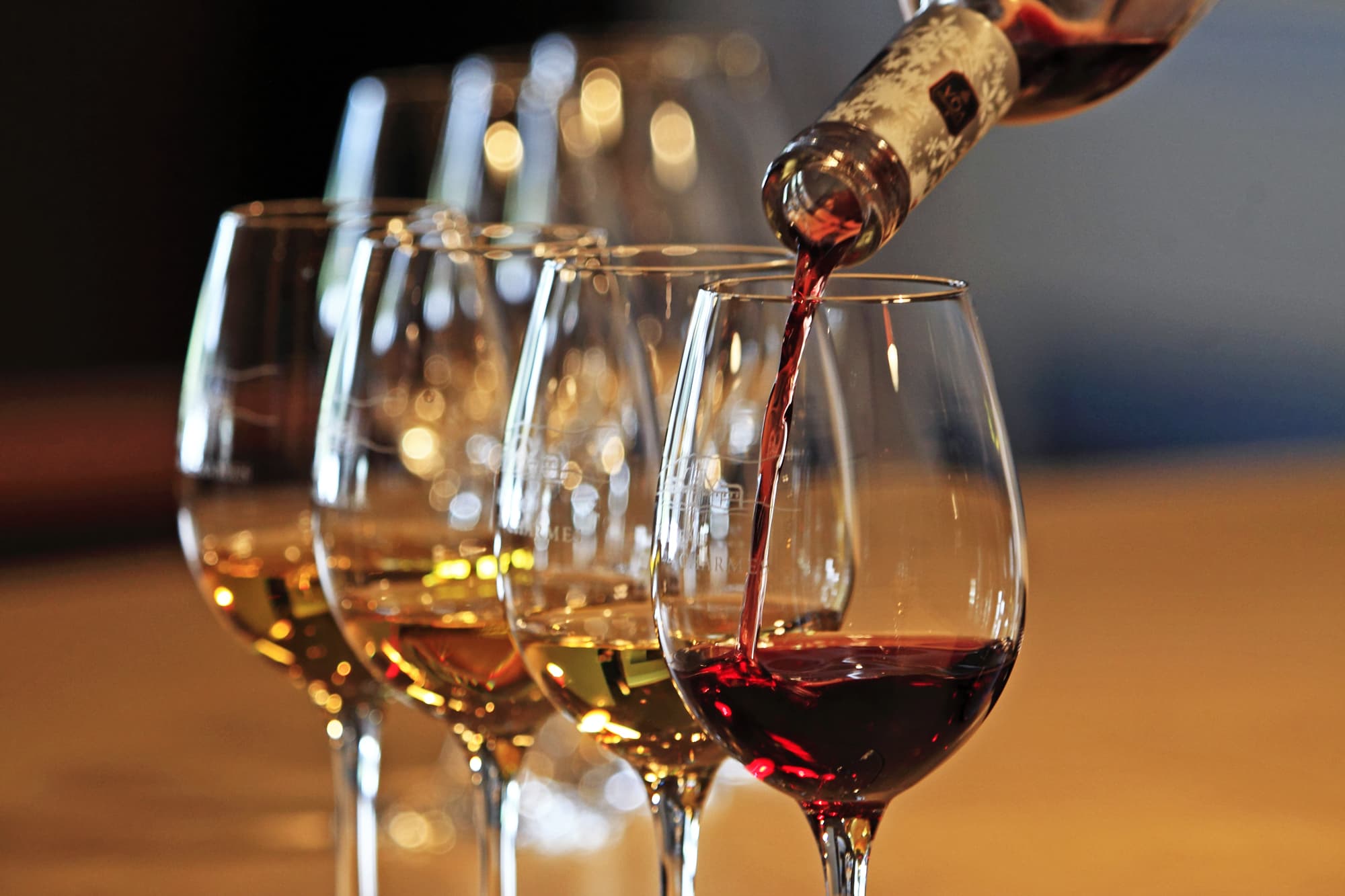 Red wine being poured alongside a flight of whites